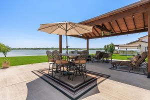un patio con mesa, sillas y sombrilla en Lakefront Family Vacation Home close to Frisco and Dallas, en Little Elm