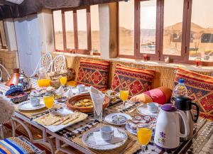 マハミドにあるLes voix de Sahara Lodgeの食べ物とオレンジジュースが入ったテーブル