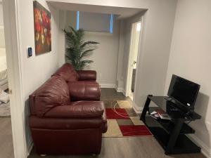 sala de estar con sofá de cuero marrón y TV en Calm & Cozy 2 Queen Bedroom Suite, en Niagara Falls 10 fotos más
