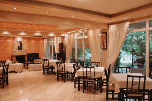 a dining room with tables and chairs and a piano at Enastron Hotel in Kato Loutraki