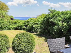 a yard with two chairs and bushes and the ocean at 8 person holiday home in Asperup in Asperup