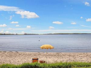 una sombrilla amarilla en una playa con agua en 18 person holiday home in N rre Aaby en Føns