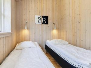 Habitación con 2 camas y paredes revestidas de madera. en Holiday Home Skovbrynet II, en Odde
