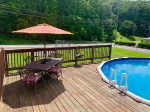 una terrazza in legno con tavolo e ombrellone accanto alla piscina di Brick By The Bridge - POOL! a Fayetteville