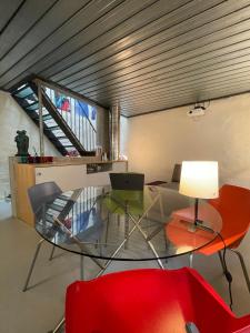 Habitación con mesa de cristal y silla roja. en Loft-House - Maison Vigneronne Village UNESCO, en Rivaz