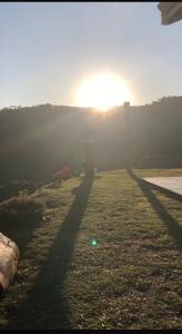Zwei Schatten von zwei Menschen auf einem Feld bei Sonnenuntergang in der Unterkunft Casa Aconchegante na Montanha in Campos do Jordão