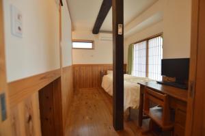 sypialnia z łóżkiem i biurkiem z telewizorem w obiekcie Guest House Ilonggo w mieście Tsu