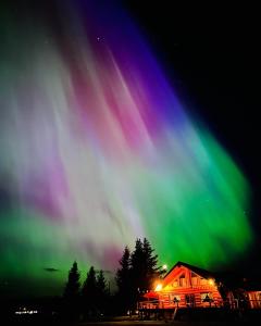 una imagen de la aurora boreal en el cielo sobre una cabaña en Cariboo Log Guest House, en Lac La Hache