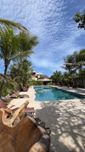 a large swimming pool with palm trees in a resort at Pousada Rio das Onças in Fortim