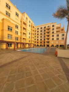a large building with a swimming pool in front of it at Lotus Apartments in King Abdullah Economic City
