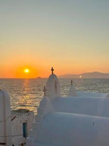 - un coucher de soleil sur l'océan avec une église au premier plan dans l'établissement Myconian Little Venice Elite Suites with Sea View, à Mykonos