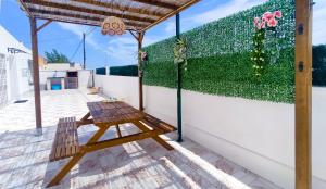 eine Holzbank auf einer Terrasse mit einer grünen Wand in der Unterkunft CASA SOLEADA. Intimidad, piscina y mucho sol. in Santiago de la Ribera