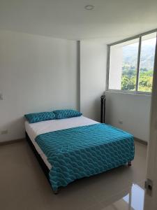 a bed in a white room with a window at Citadela Disole Paraíso in Santa Fe de Antioquia