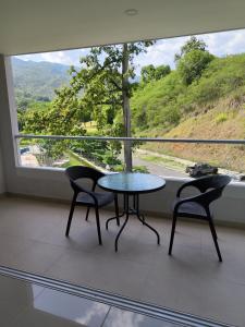 un tavolo e due sedie in una stanza con una grande finestra di Citadela Disole Paraíso a Santa Fe de Antioquia