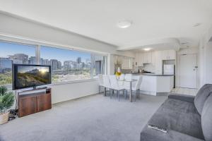 een woonkamer met een bank en een tv en een keuken bij Sydney Harbour View Apartments in Sydney
