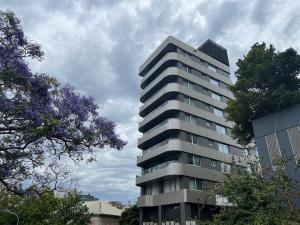 een hoog grijs gebouw met bomen ervoor bij Sydney Harbour View Apartments in Sydney