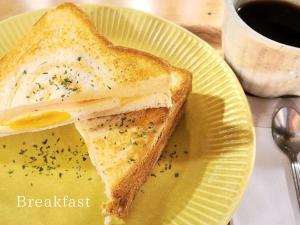 a grilled cheese sandwich on a yellow plate with a cup of coffee at Guest House Pongyi in Kanazawa