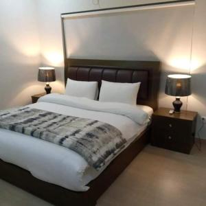 a bedroom with a large bed with two tables and two lamps at Karachi Airport Hotels in Karachi