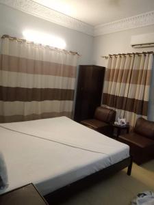 een slaapkamer met een bed, een bank en gordijnen bij Karachi Airport Hotels in Karachi