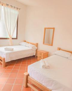 two beds in a room with a mirror and a window at Hotel Villa Santa María in Santa Fe de Antioquia +16 photos