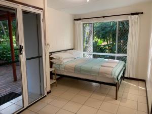 sypialnia z łóżkiem i dużym oknem w obiekcie Shambhala Retreat Magnetic Island Cottages w mieście Nelly Bay
