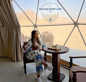 Una donna seduta a un tavolo con una tazza di caffè di Wadi Rum desert camp a Wadi Rum