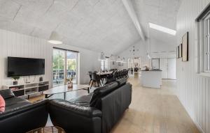 a living room with black leather furniture and a dining room at Amazing Home In Blåvand With Sauna in Blåvand