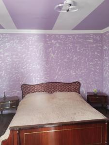 a bedroom with a bed with a purple wall at Dava in Gyumri