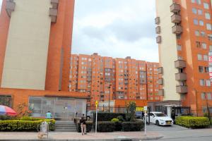 un grand bâtiment en briques avec des personnes debout devant lui dans l'établissement Acogedor Apartamento en zona residencial con vista a la ciudad Wi-Fi 350 Mbps, à Bogotá