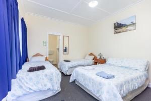 ワンガヌイにあるBraemar House B&B and YHA Hostelの青いカーテンが備わる客室のベッド2台