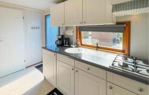 a kitchen with white cabinets and a sink and a window at Pet Friendly Stacaravan In Tzummarum in Tzummarum