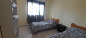 a small room with two beds and a window at Departamento ANGOSTURA in General Alvear