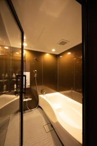 a bathroom with a bath tub and a shower at HOSTEL perch in Sado
