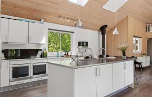 a kitchen with white cabinets and a sink at Holiday Home Tværvænget Blåvand in Ho