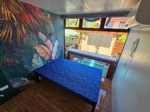 um quarto com um banco azul em frente a um mural em Jolie Joe's Bed and Breakfast em Tagudin