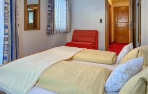 ミュールバッハ・アム・ホーホケーニッヒにあるAmazing Apartment In Mhlbach With House A Mountain Viewのベッド2台と赤い椅子が備わる客室です。