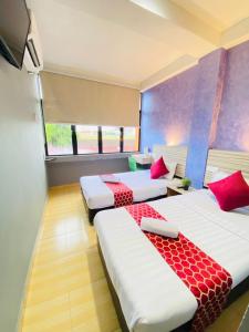 Habitación con 3 camas con almohadas rojas. en DJ Citi Inn Premier en Kuala Terengganu