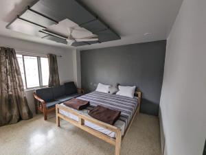 a bedroom with a bed and a couch in it at Swanky Sojourns Home Stay with AC bedroom in Kolhapur