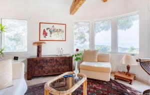 a living room with a couch and a chair and windows at 2 Bedroom Awesome Home In Les Issambres in La Garonnette-Plage