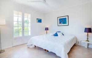 a white bedroom with a large white bed with blue pillows at 2 Bedroom Awesome Home In Les Issambres in La Garonnette-Plage +19 photos