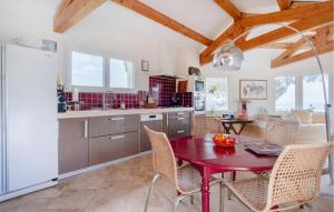 a kitchen with a red table and chairs in a kitchen at 2 Bedroom Awesome Home In Les Issambres in La Garonnette-Plage
