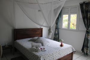 a bedroom with a bed with towels and a window at Le Colibri et le Frangipanier in La Trinité