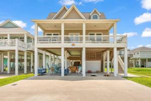 ein großes Haus mit einer großen Veranda mit einer Terrasse in der Unterkunft Hot Tub, Gas Grill, Tiki Bar w/TV, Dog Friendly in Bolivar Peninsula
