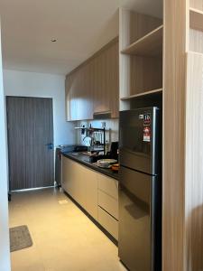 a kitchen with a black refrigerator and wooden cabinets at SS Staycation @Roxy Sematan Beach Apt in Sematan