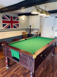 uma mesa de bilhar verde num quarto com bandeira em Blue Bell em Rothwell