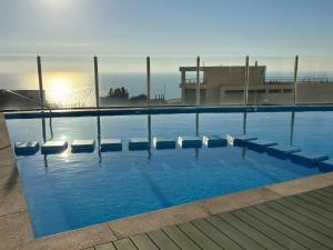 Una piscina con sillas y el océano al fondo. en VISTAMAR COSTAHORIZONTE CONCON, en Concón