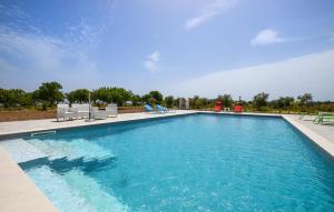 a large swimming pool with blue water and chairs at 2 Bedroom Amazing Home In Noto in Noto +16 photos