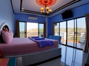 a bedroom with a bed with blue walls and windows at Ocean View Resort - Koh Sichang in Ko Si Chang