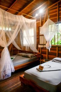 twee bedden in een kamer met klamboes bij La tarima del colibri Ecolodge in El Valle