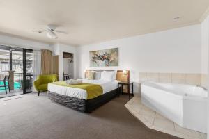 a bedroom with a large bed and a bath tub at Tuscany Villas Whakatane in Whakatane
